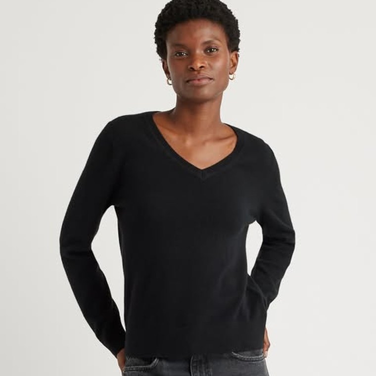 A Quince ad: a woman in a black cashmere V-neck sweater against a plain background