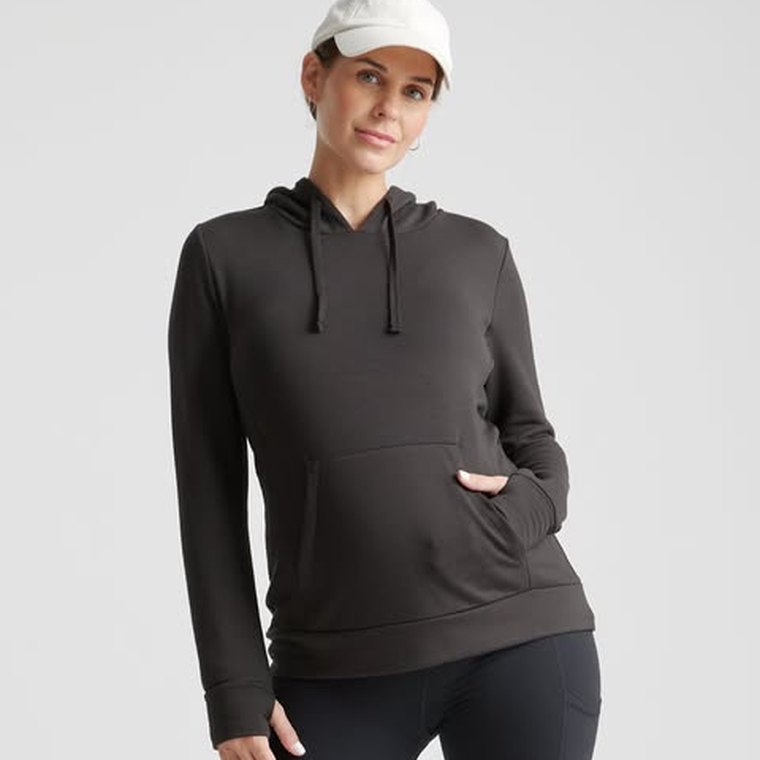 A Quince ad: a pregnant woman in a dark hooded sweatshirt and a white cap