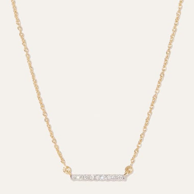 A Quince ad: a gold chain necklace with a small diamond bar pendant on a cream background