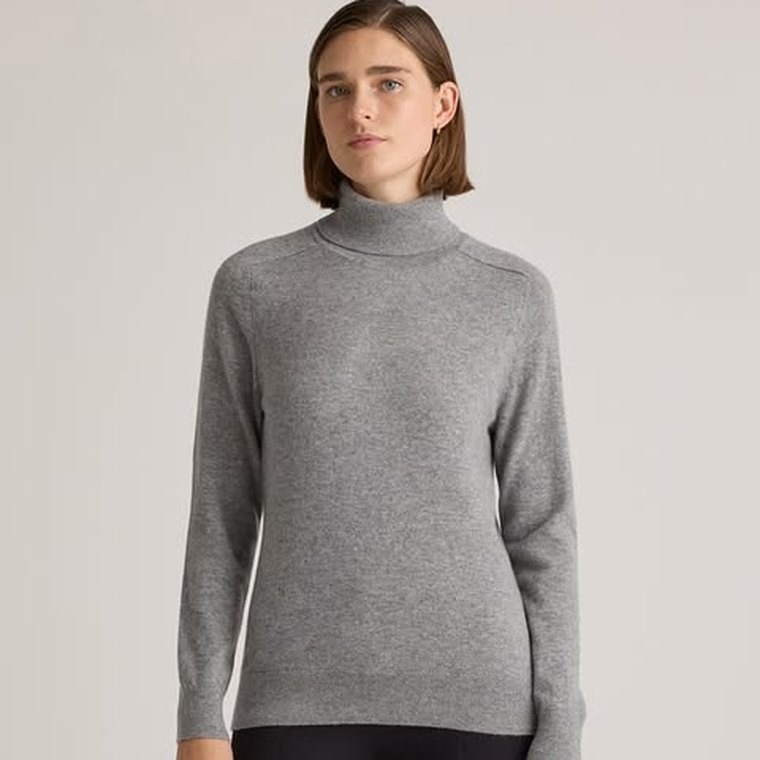 A Quince ad: a woman in a grey cashmere turtleneck against a plain background