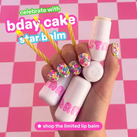 A Starface ad creative: a hand holding birthday cake star balms and sprinkle-covered patches with candles, on a pink checkerboard