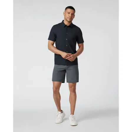 A Vuori ad creative: a man in a black short-sleeved shirt, grey shorts and white trainers against a plain background