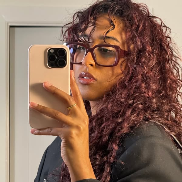 An ad by Warby Parker in Meta's Ad Library: a creator with curly hair takes a mirror selfie in burgundy Warby Parker frames, with no text on the picture