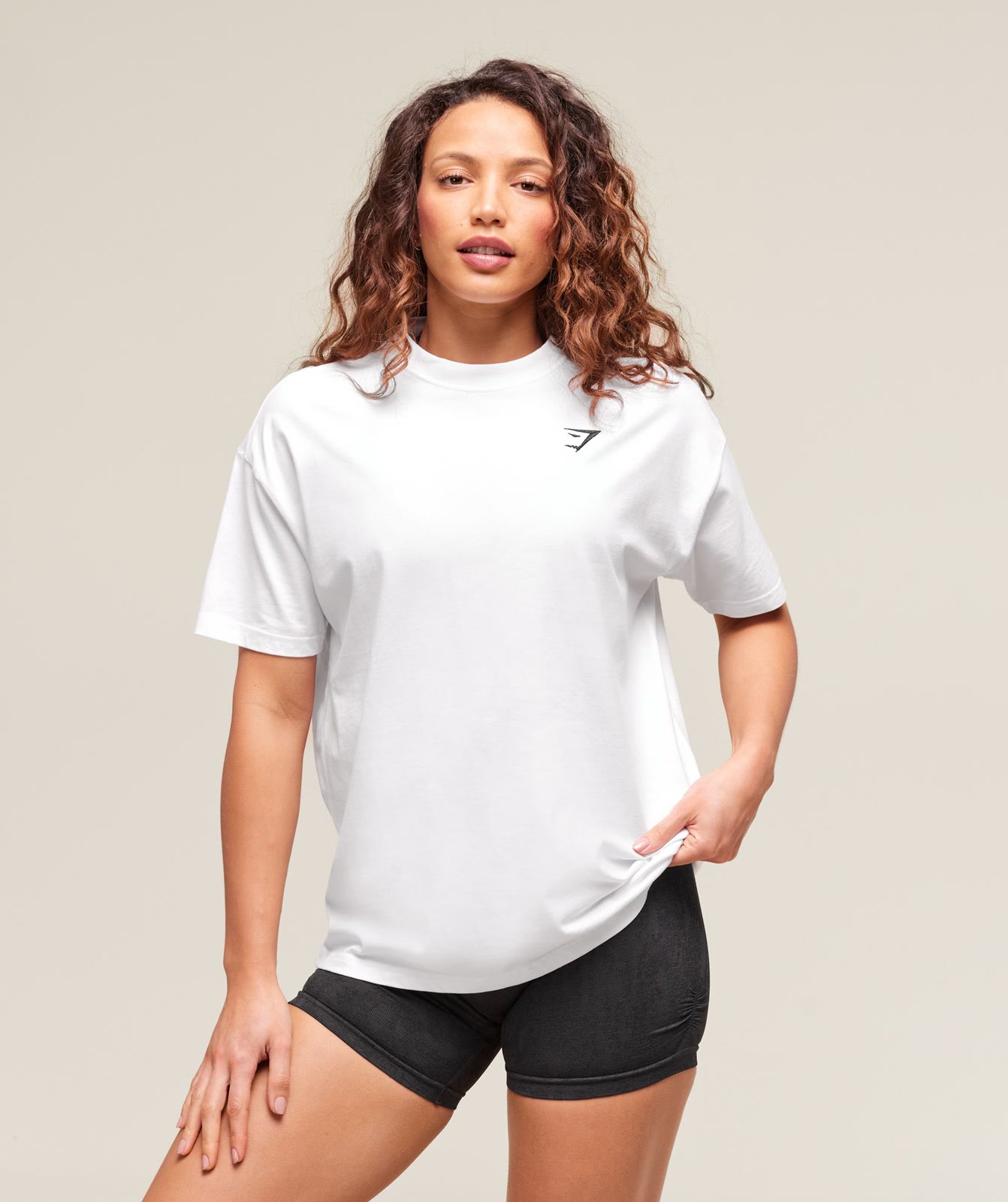 A catalog ad by Gymshark in the Meta Ad Library: a model in a white T-shirt and black shorts, with the offer only in the text