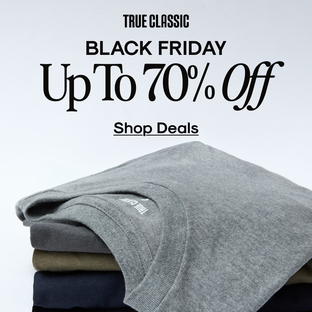 An ad by True Classic in the Meta Ad Library: Black Friday, Up To 70% Off, Shop Deals, over a stack of folded T-shirts