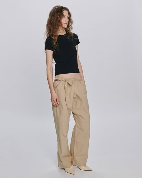 An ad by ATM Anthony Thomas Melillo in Meta's Ad Library: a model in a black t-shirt and beige tie-waist pants stands in a white studio, in an ad that invites you to meet the Judo Pant