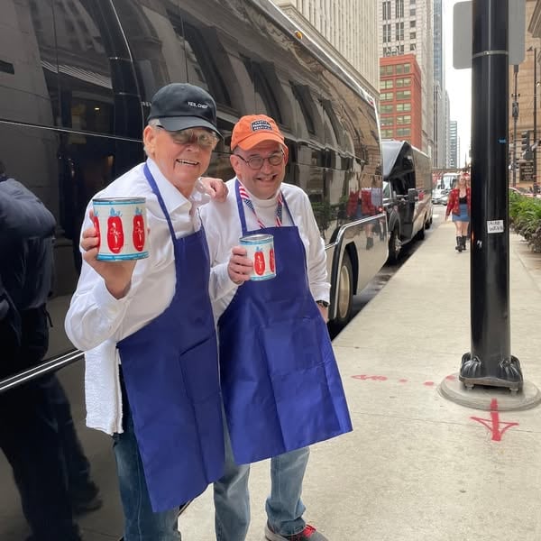 An ad by Chicago Food & City Tours in Meta's Ad Library: two men in aprons hold tomato cans beside a tour bus, for a food tour of restaurants seen in the TV show The Bear