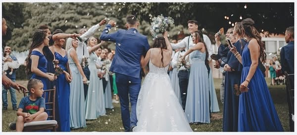 An ad by Simple Canvas Prints in Meta's Ad Library: a bride and groom walk between guests in blue dresses, for a blog post on 4 ways to display photos during your wedding day
