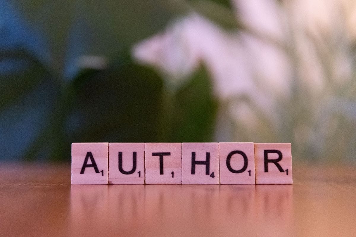 Letter tiles spell the word author on a wooden table: taglines are the shortest copy a brand writes and the longest it keeps