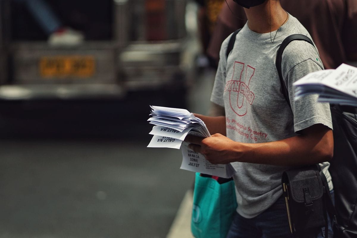 A man hands out printed flyers on a busy street corner: a call to action has about two seconds to make the next step feel small