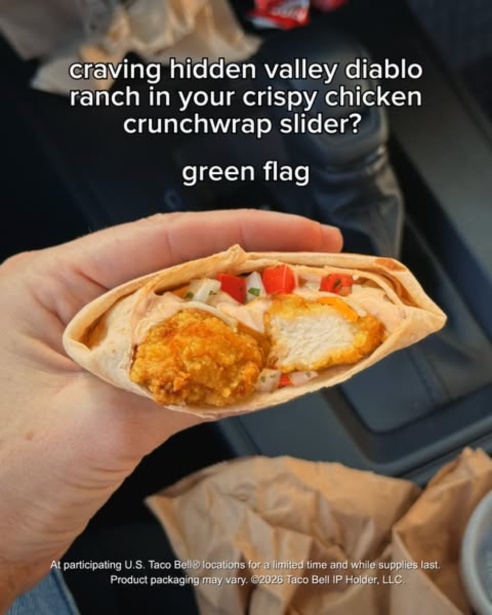 An ad by Taco Bell in the Meta Ad Library: a hand holds a cut crispy chicken crunchwrap slider in a car, captioned green flag