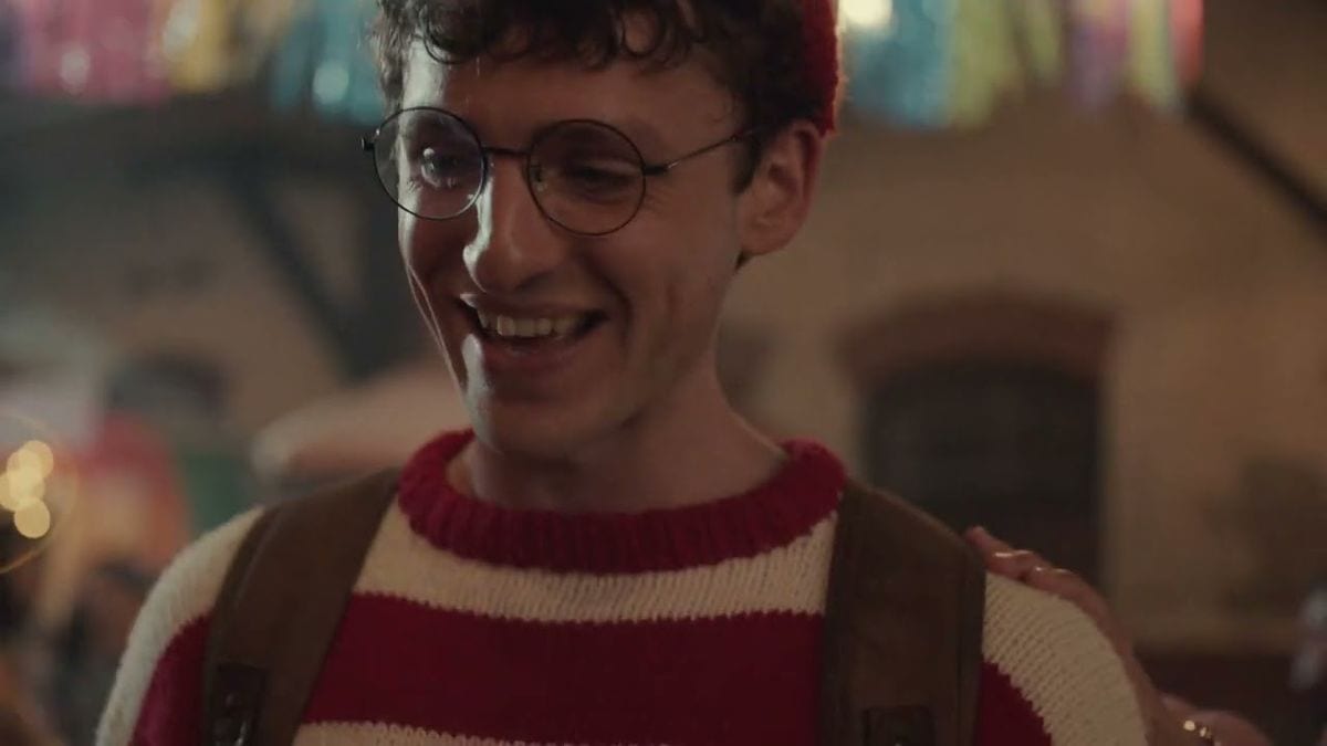 A still from Etsy's 2024 holiday ad Where's Waldo: Waldo smiles in his red and white striped sweater and round glasses at a warm, lit party