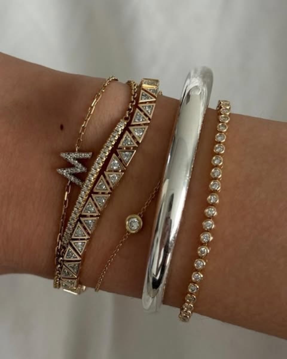 An ad by Mejuri in the Meta Ad Library in 4:5: a wrist with stacked gold and silver bracelets, shot by a creator