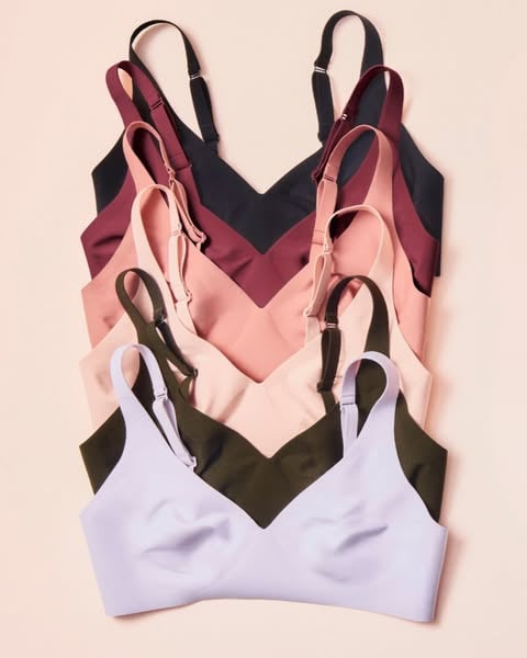 An ad in Meta's Ad Library: six bras in black, wine, pink, peach, olive and lilac fanned out on a peach background