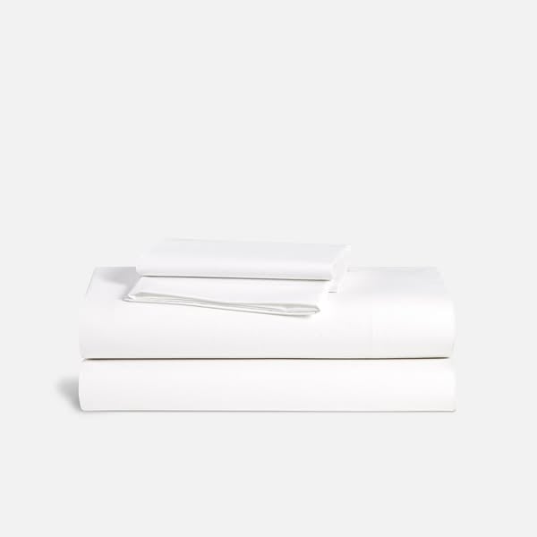 An ad by Brooklinen in Meta's Ad Library: a folded stack of white sheets and pillowcases on a gray background