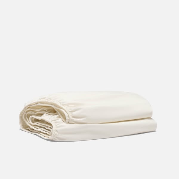An ad by Brooklinen in Meta's Ad Library: a folded ivory fitted sheet on a gray background