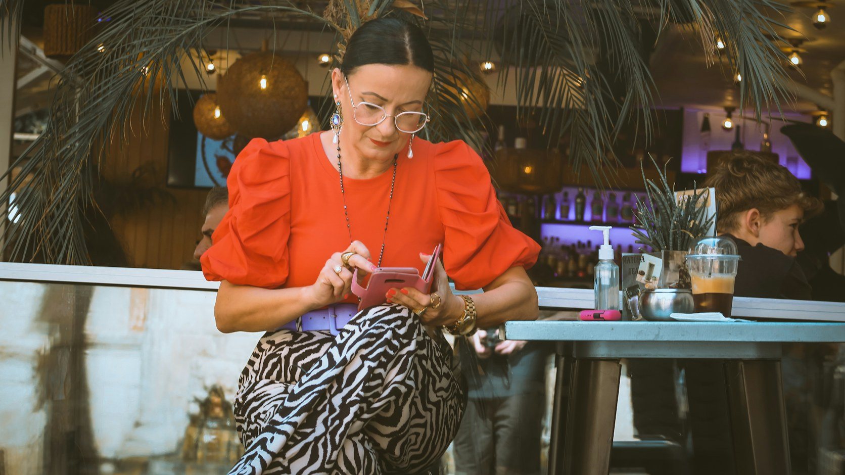 A woman in a café typing on her phone, the moment most Instagram captions get written