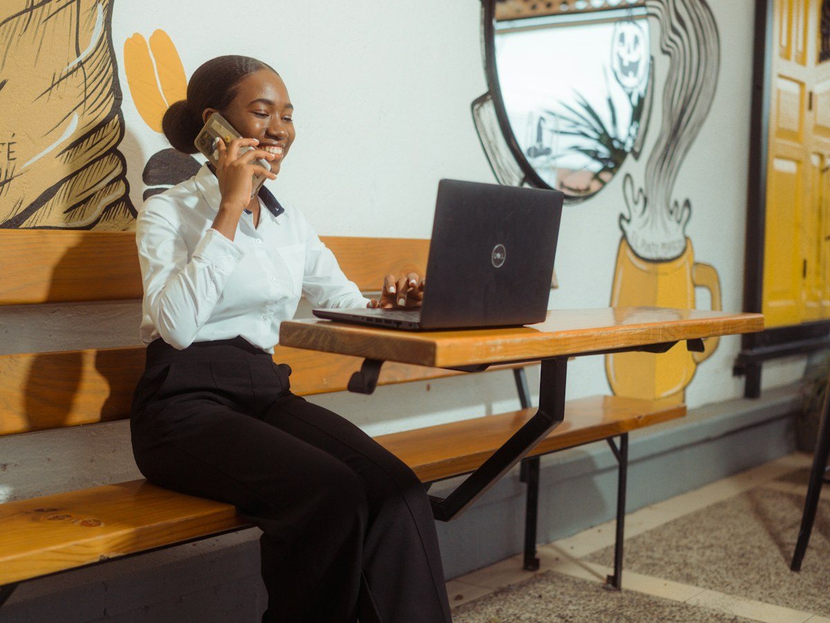 A woman at her laptop in a café, on a call: most business captions are written between two other jobs, which is why the first line gets the least thought