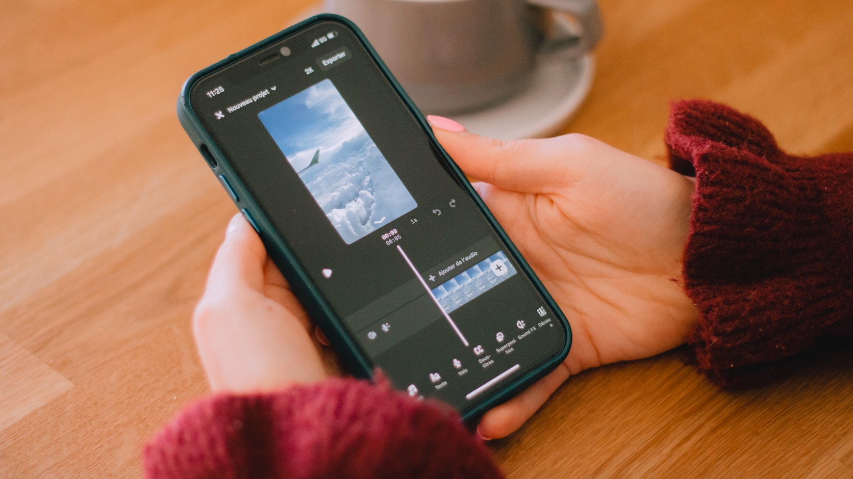 A phone showing an editing timeline, mid-export, held over a desk