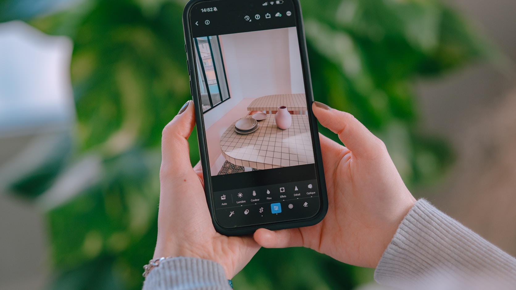 Hands holding a phone, framing a shot before it is taken: the crop is decided here, not at upload