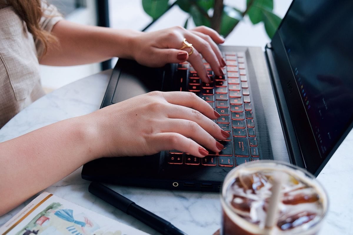 Hands typing on a laptop next to an iced coffee: a LinkedIn post that starts from real work, written in one sitting