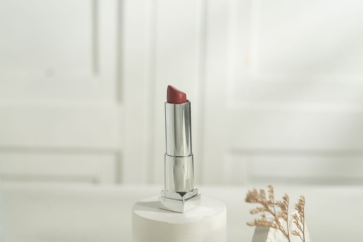 A lipstick standing on a white plinth with dried flowers: a clean product shot with space for one headline, the default static layout