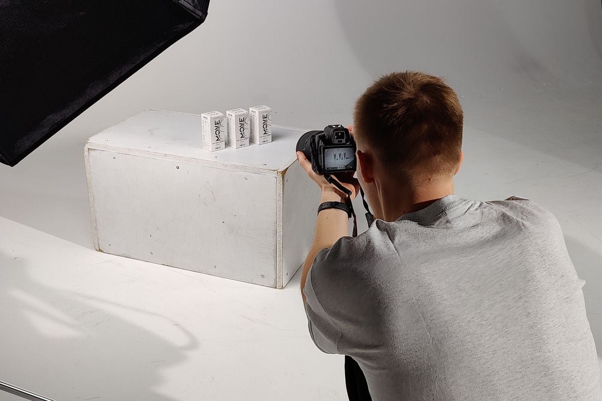 A photographer shooting a product on a white set in a studio: one shoot like this can feed a whole batch of static ads