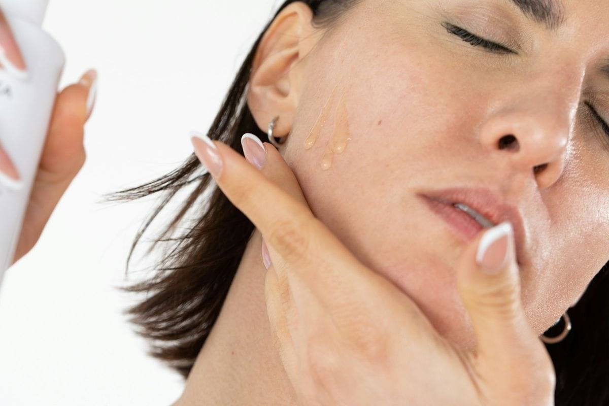 A close-up of a woman applying skincare to her cheek: skincare is one of the categories where before-and-after statics are common and restricted