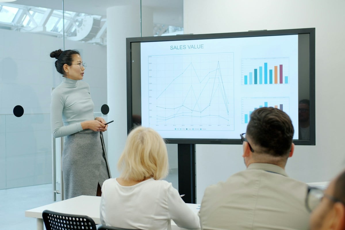 A woman presenting a results chart on a screen to colleagues: a static is called a winner only after it has had enough spend