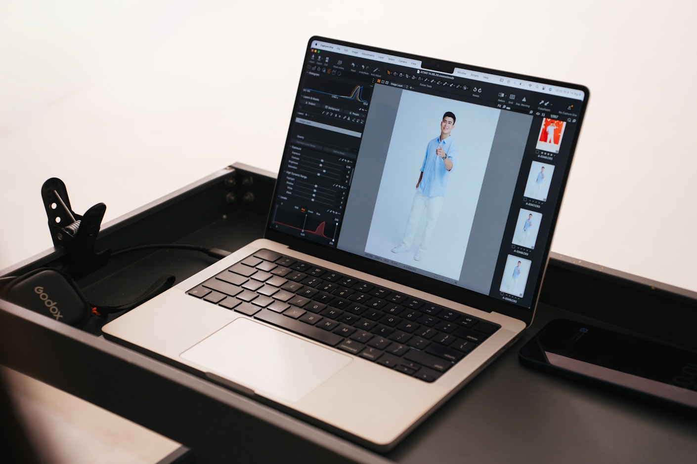 A laptop on a bright desk showing photo editing software with an image of a person open in it