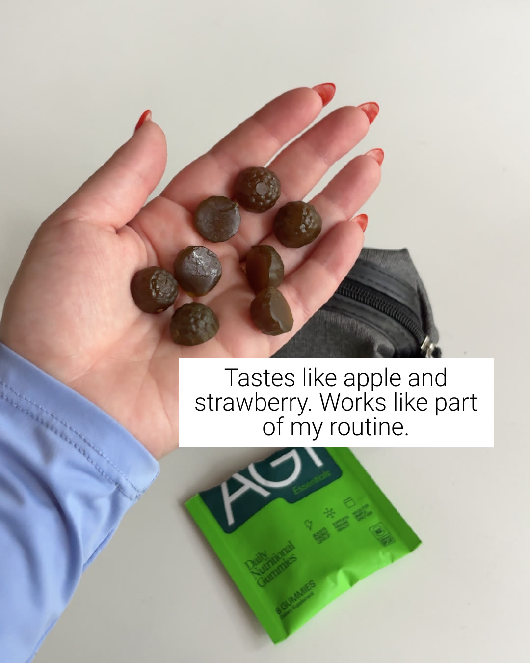 An AG1 static ad on Meta: a hand holding AG1 gummies over the pouch, captioned tastes like apple and strawberry, works like part of my routine