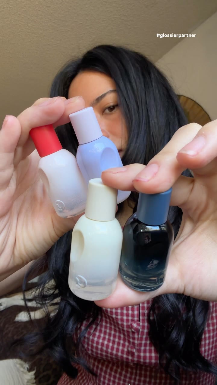 A Glossier creator ad on Meta: a woman holding the mini Glossier You perfume bottles up to the camera at home