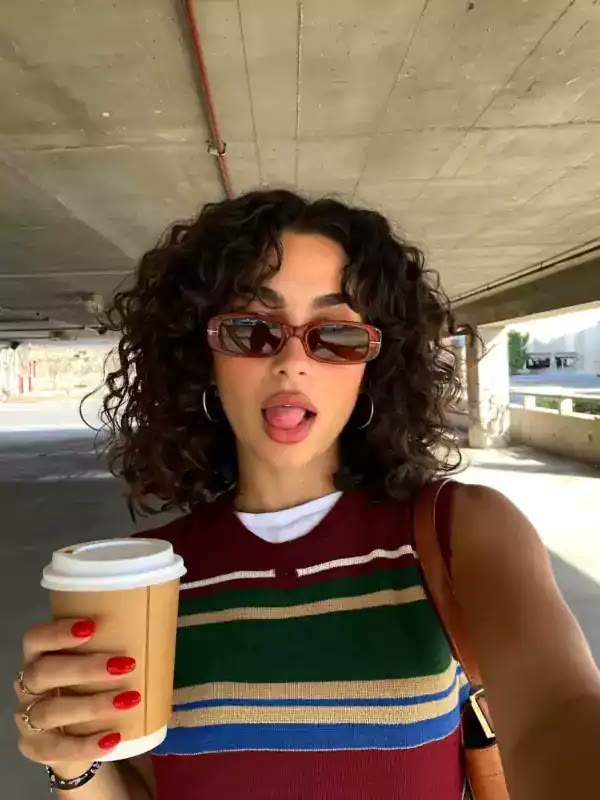 A Higgsfield UGC template: a selfie of a woman in sunglasses holding a coffee cup