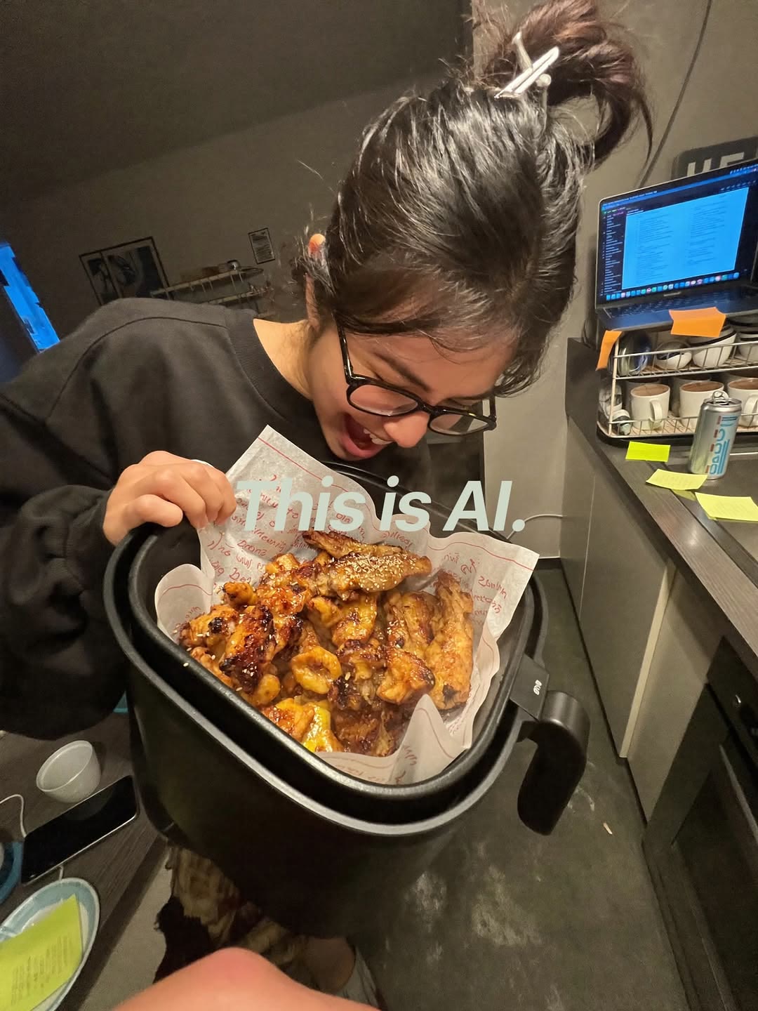 An AI-generated phone-style shot of a woman opening an air fryer of chicken wings in a home kitchen, stamped This is AI.